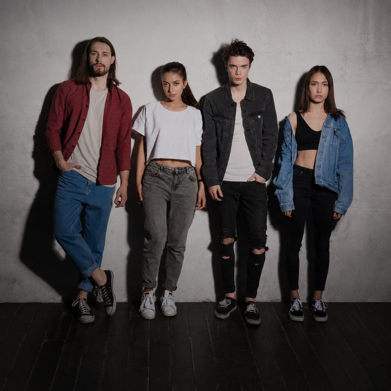 four diverse fashion models posing together against a plain grey wall